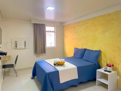 累西腓Hotel Boa Viagem Aeroporto的一间卧室配有一张蓝色的床,上面有一碗水果