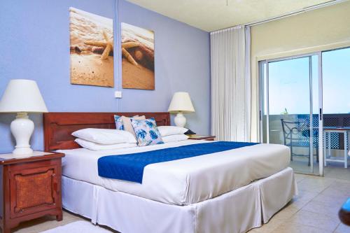 圣詹姆斯热带日落海滩公寓式酒店的一间带大床的卧室和一个阳台