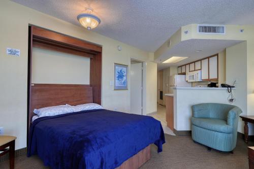 默特尔比奇1604 N Ocean Blvd, 0703 - Ocean Front Sleeps 6的一间卧室配有一张床和一把椅子,一间厨房