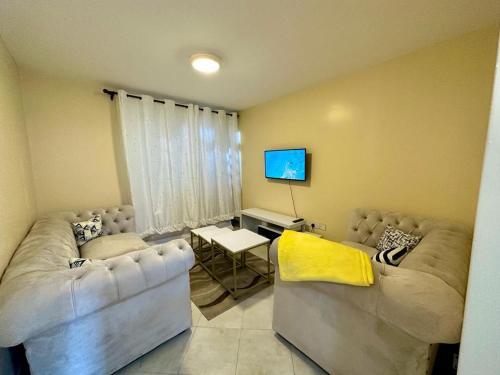 ThikaCandy's Staycation的客厅配有两张沙发和一台电视机