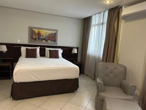 马瑙斯Millenium Hotel Flat的配有一张床和一把椅子的酒店客房