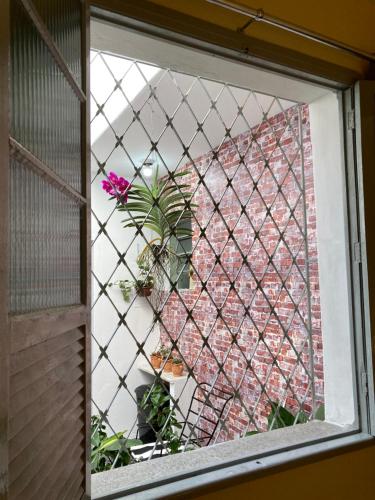 贝洛奥里藏特Casinha do Prado, conforto vintage, ar condicionado的砖墙的窗户,盆栽植物