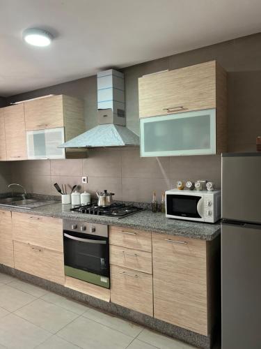 西迪布克纳德尔Luxury Apartement Near the Beach的厨房配有木制橱柜和微波炉。