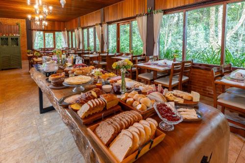 蒙特韦尔迪Pousada Cerejeiras的长桌,长桌里摆放着许多不同类型的面包
