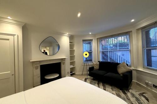 伦敦Chic Studio Flat 8 Mins to Harrods Knightsbridge的客厅配有黑色沙发和镜子