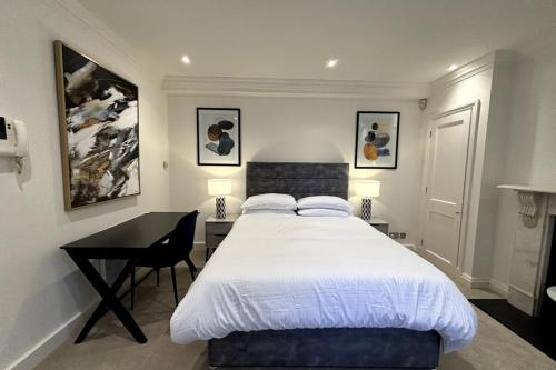 伦敦Chic Studio Flat 8 Mins to Harrods Knightsbridge的一间卧室配有一张床和一张书桌,配有一张四柱床