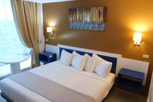 伯利兹城Golden Tree Hotel Belize的配有白色枕头的床的酒店客房