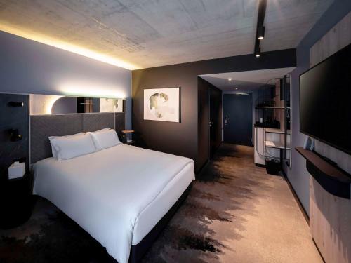 德莱蒙Mercure Hotel Delémont的卧室配有一张白色大床和一台平面电视。