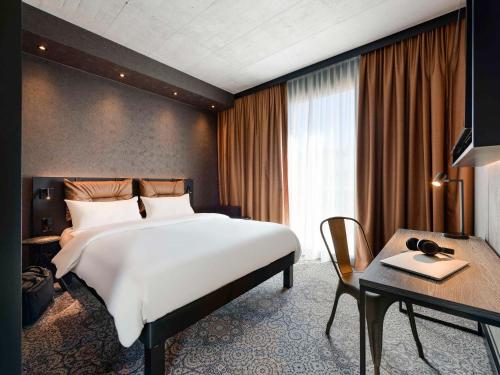 腓特烈港ibis Styles Friedrichshafen的酒店客房设有一张大床和一张书桌。