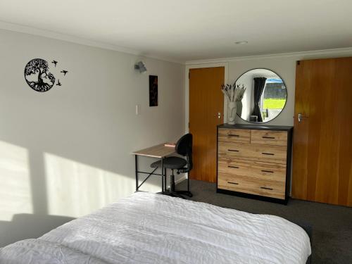 惠灵顿Hill View Abode Tawa的一间卧室配有一张床、一张书桌和一面镜子
