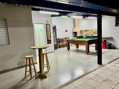 佩鲁伊比Casa aconchegante em Peruíbe的一间带台球桌和两张凳子的房间