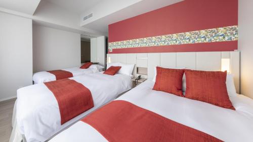 那霸Hewitt Resort Naha的红色和白色的客房内的两张床