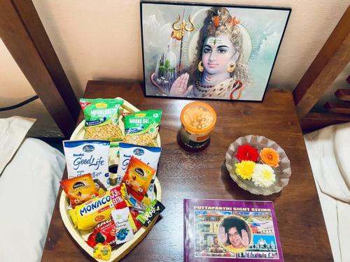 普塔帕蒂Shanthi Home Stay的一张桌子,上面有小吃和一张女人的照片