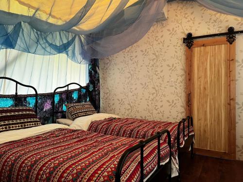 Setoウッドデザインパーク瀬戸的卧室设有两张单人床和窗帘