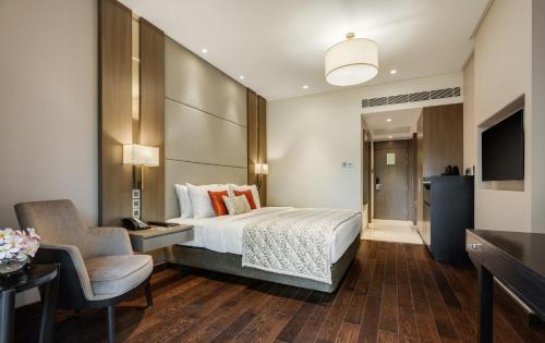 班加罗尔Palm Meadows Resort的配有一张床和一把椅子的酒店客房