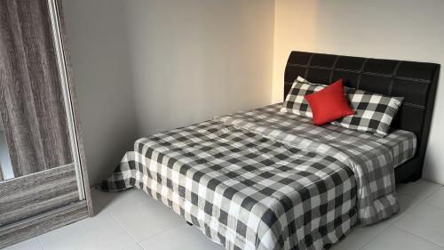 斯里曼绒Spacious+Minimal+Manjung City Centre的一张带 ⁇ 子毯子和红色枕头的床