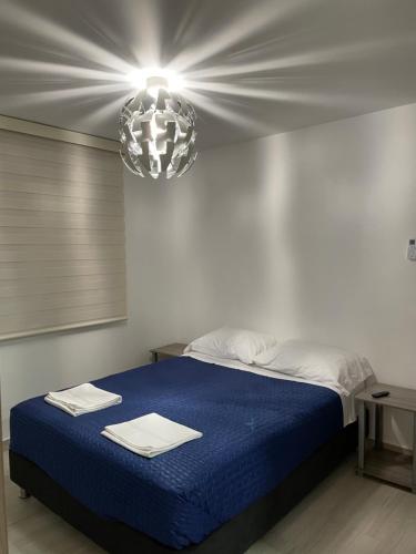里考尔特Apartamento Girardot Peñalisa con Piscina的一间卧室配有一张蓝色的床,上面有灯