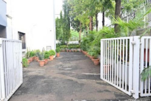 JālgaonHOTEL PRITAM PARK, Jalgaon, Maharashtra的一条有白色围栏和盆栽的车道