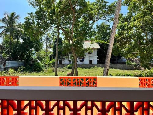 瓦尔卡拉BAVA Lalitha Retreat Center Varkala的公园里一个橙色长凳,后面有房子