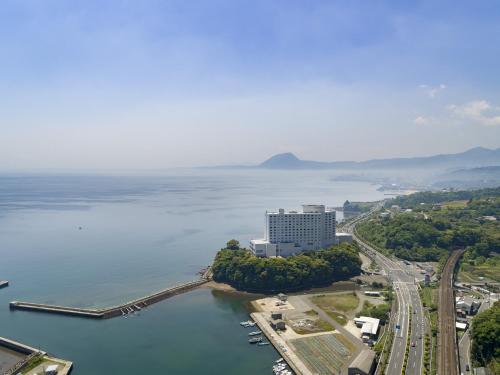 别府Grand Mercure Beppu Bay Resort & Spa的水边一座大建筑的空中景观