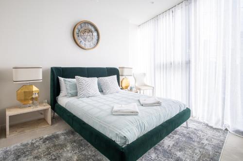 墨尔本The Cosmopolitan Crown的卧室配有一张绿色的床,墙上挂着一个时钟