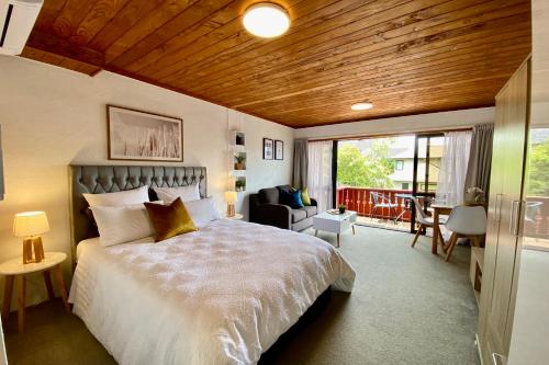 派西亚The Swiss Chalet Holiday Apartment 6, Bay of Islands的一间带大床的卧室和一个阳台