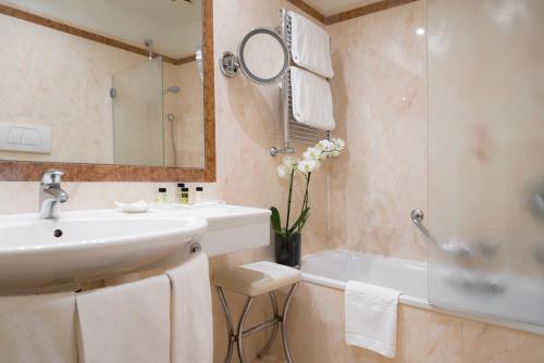 罗马戴伯尔格洛尼酒店的一间带水槽、浴缸和镜子的浴室