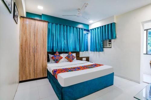 孟买FabExpress Bindra Elite的一间卧室配有一张带蓝色窗帘的大床
