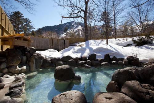 Yumoto奥日光森のホテル的积雪覆盖的院子中,积满了岩石的水池