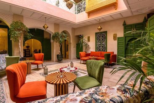 马拉喀什Riad contessa的大堂设有橙色和绿色的椅子和桌子。