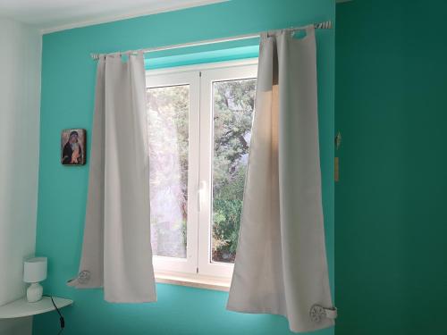 卡拉古诺内Appartamento Sole的蓝色房间中带白色窗帘的窗户
