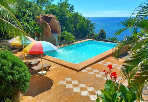 卡莫特斯群岛Camotes Serenity的一个带遮阳伞的游泳池以及大海