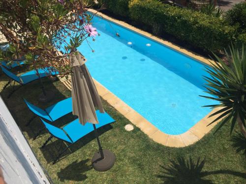 奥利维拉Only Women Guest House - Villa de la Comunidad Internacional de la Mujer的游泳池旁的遮阳伞和椅子
