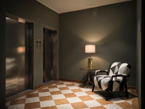 米兰Max Brown Hotel Missori, part of Sircle Collection的一间带椅子和一张桌子及台灯的房间