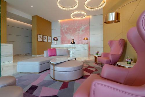 迪拜Hilton Dubai Creek Hotel & Residences的一间沙龙,里面摆放着粉色椅子,后面还有一位女士