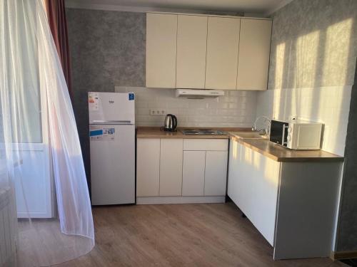 卡拉甘达Евродвушка в новостройке的小厨房配有白色橱柜和冰箱。