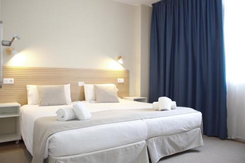 英格兰海滩Apartamentos Fayna的卧室配有一张带蓝色窗帘的大型白色床