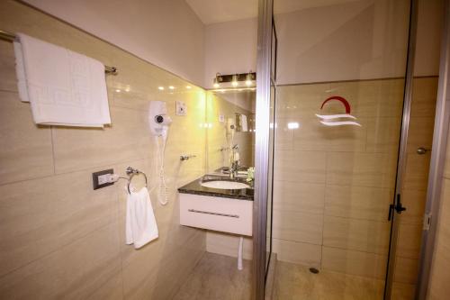 雅科Beachfront Hotel Tramonto的带淋浴和盥洗盆的浴室以及电话。