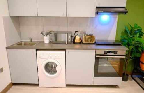 伦敦GoldersGreen Apartments by Sleepy的厨房配有洗衣机和水槽