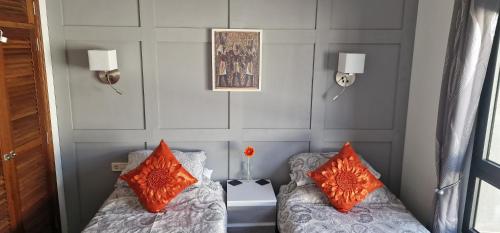 普拉亚布兰卡Casa De Nefertiti的客房 - 带两张带橙色枕头的床