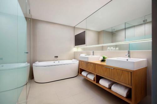 悉尼悉尼中央公园福朋喜来登酒店的浴室设有2个水槽、浴缸和镜子