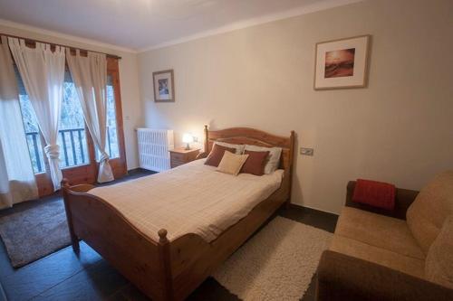 厄茨XALET CARLEMANY (Casa entera /hab.)的一间卧室配有一张木床和一张沙发