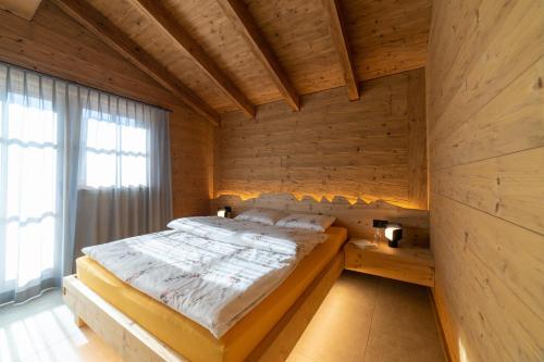 维尔德豪斯Chalet Gamserrugg的木制客房内的一间卧室,配有一张床