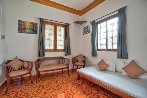 安君纳Villa Seafront Goa的客房设有一张床、椅子和窗户。