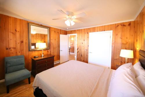 大洋城Surf Villa Apartments的一间卧室配有一张床、一把椅子和吊扇