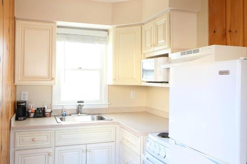 大洋城Surf Villa Apartments的厨房配有白色橱柜、水槽和冰箱。