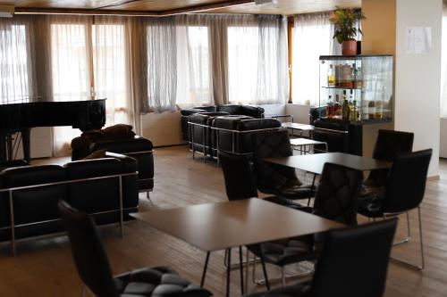 摩德纳迪-坎皮格里奥格力弗恩斯泰尔酒店的一间设有桌椅和钢琴的等候室