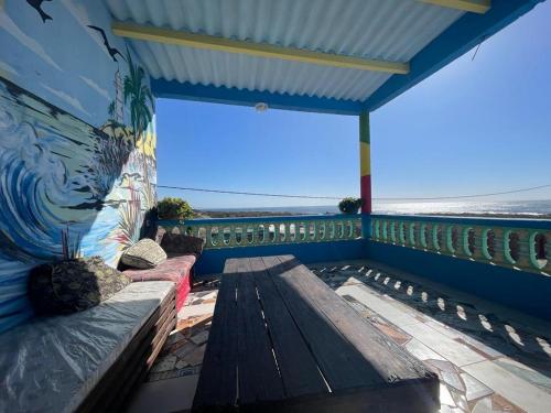 TamriBoilers Surf House的阳台设有长凳,墙上挂着一幅画