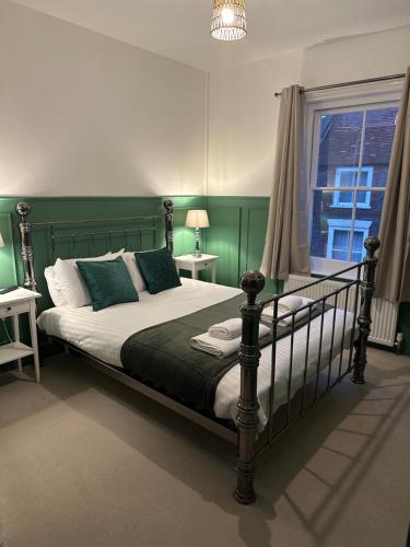新港韦弗利宾馆的一间卧室设有一张带绿色墙壁和窗户的床。