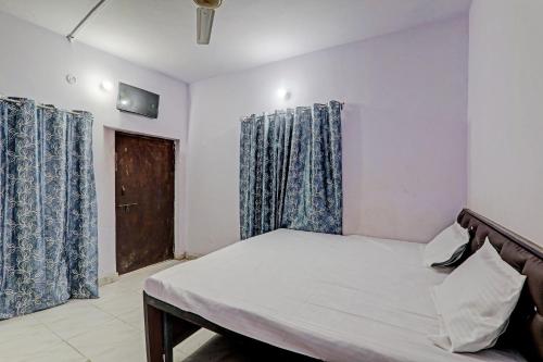 勒克瑙Gracious Guest House的一间卧室配有一张带蓝色窗帘的床和一扇门
